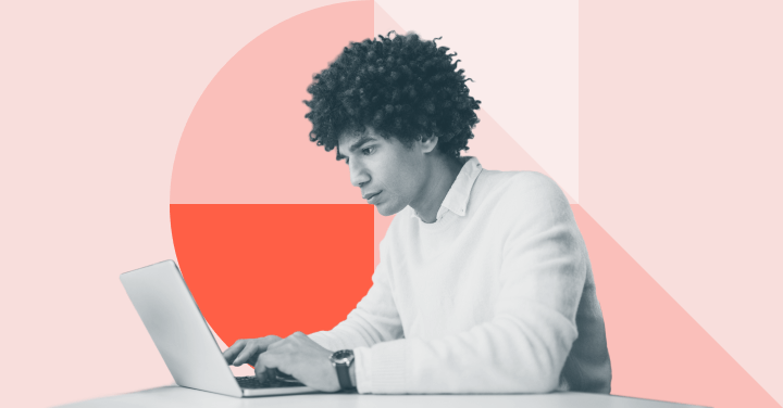 Man with curly hair typing on a laptop at a desk.