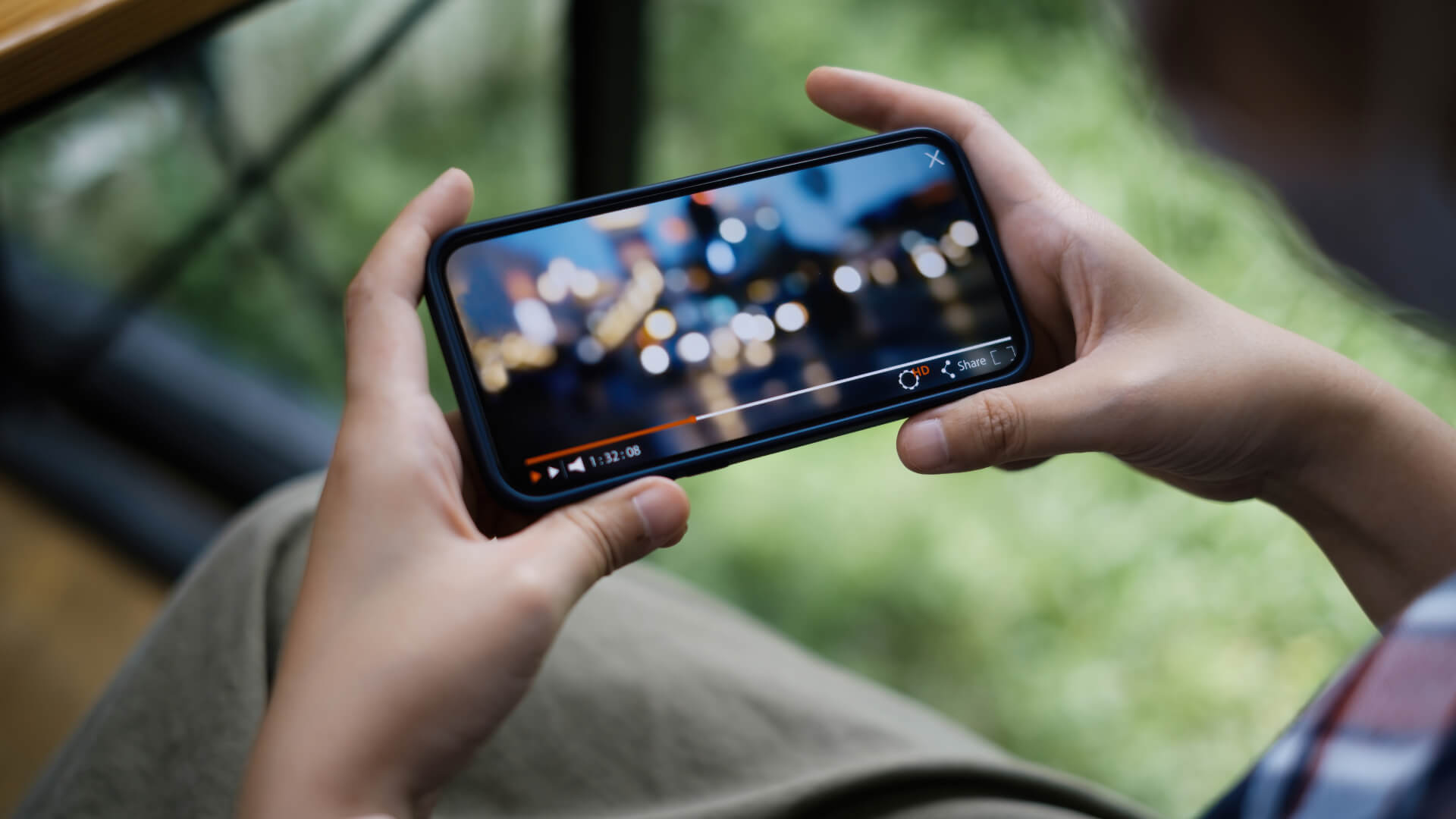Person holding smartphone watching a video outdoors.