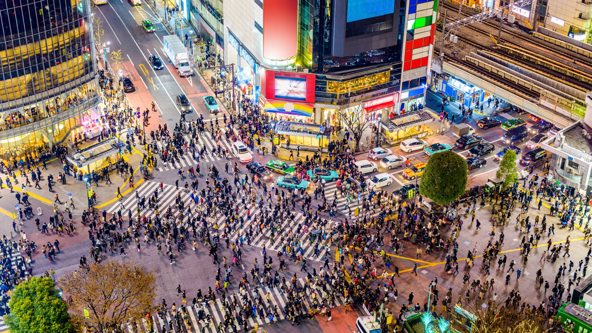 Aerial view of crowded urban intersection with pedestrians and vehicles.