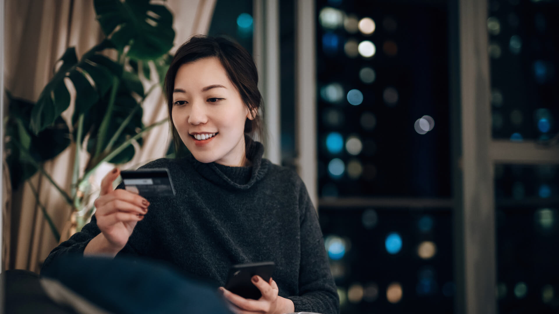 Woman shopping online with credit card at night
