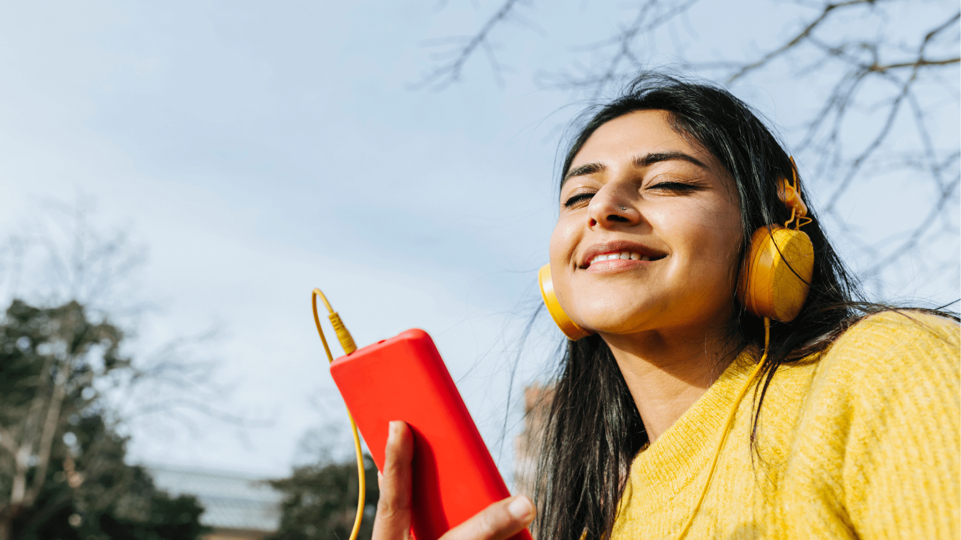Woman in yellow sweater enjoying music with headphones