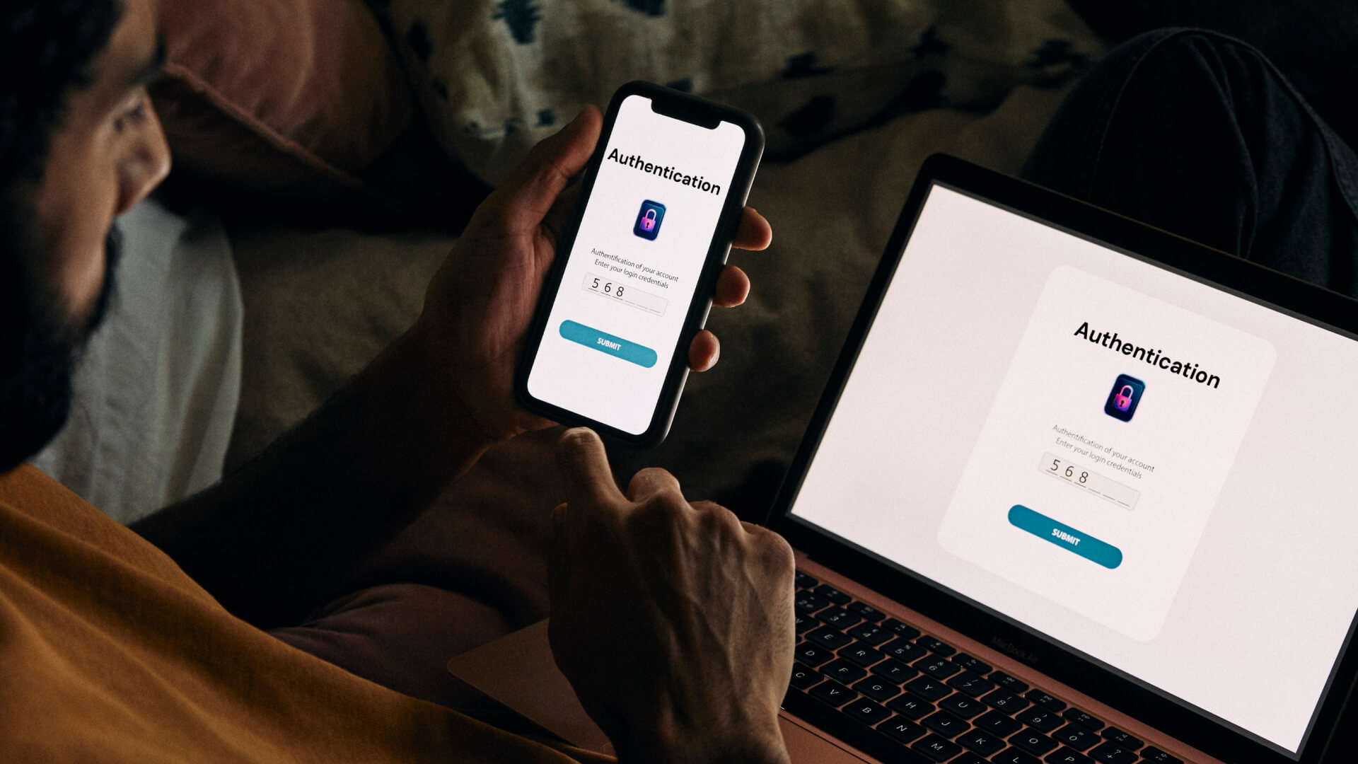 Person entering authentication code on phone and laptop