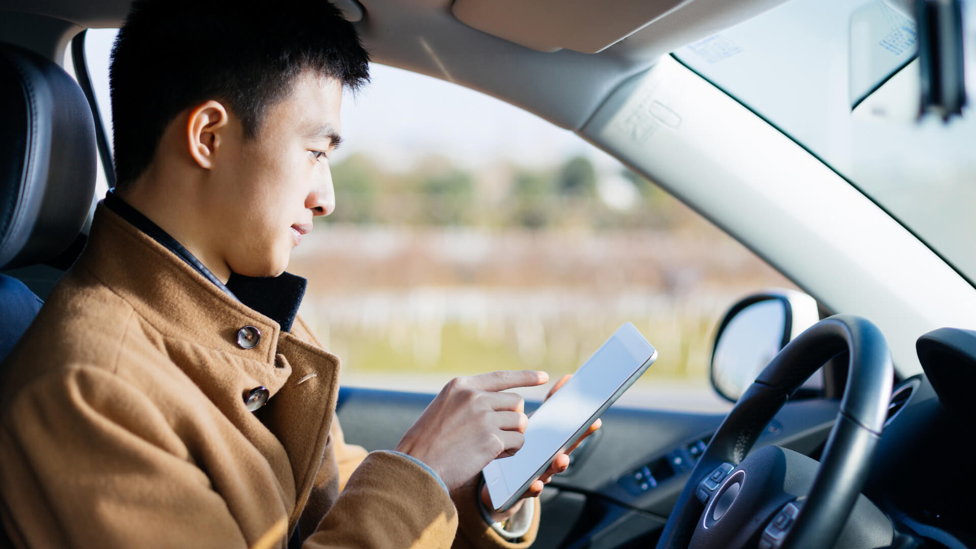 Man using a tablet while sitting in a car.