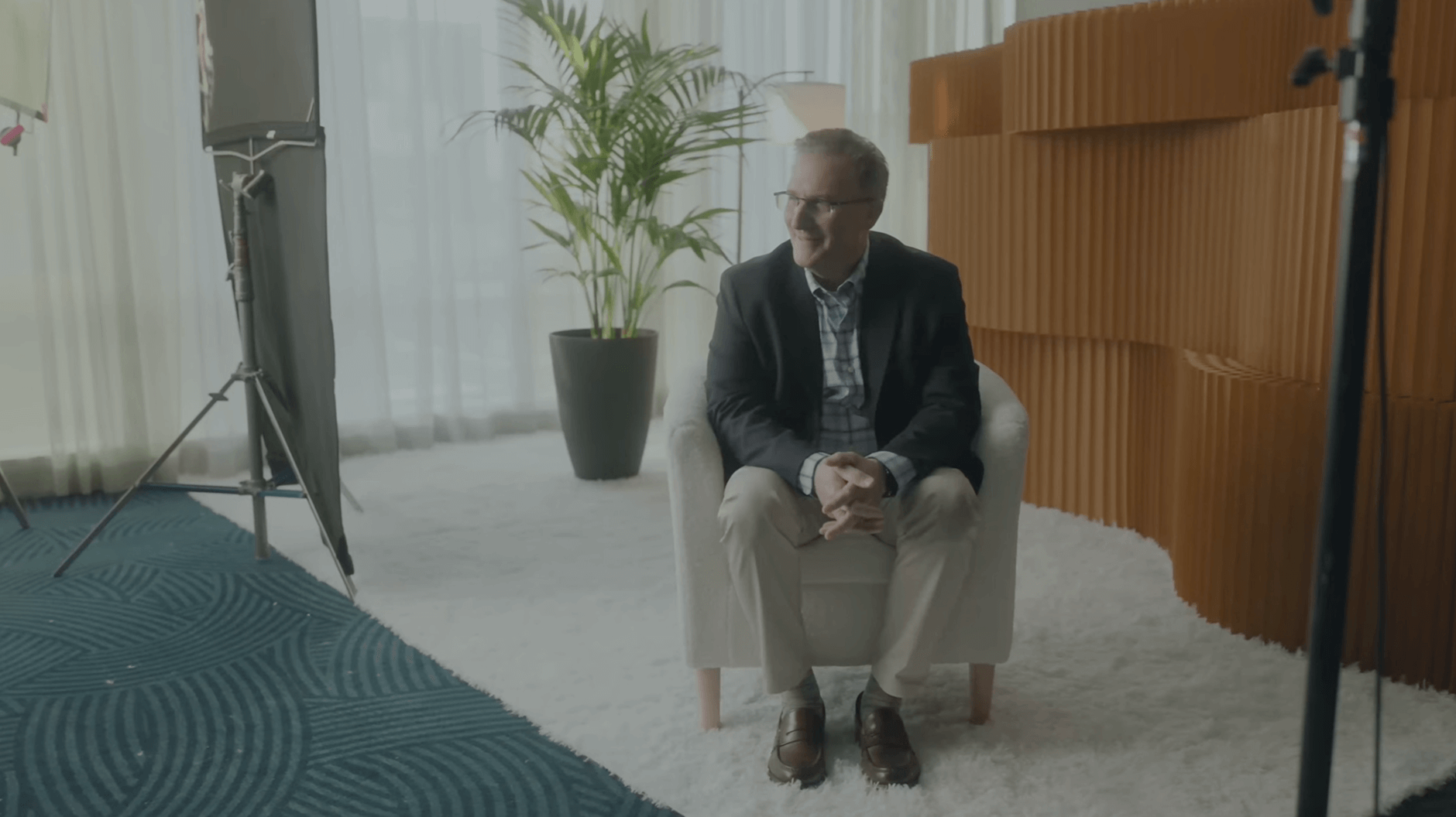 A man sitting on a chair with his hands clasped.