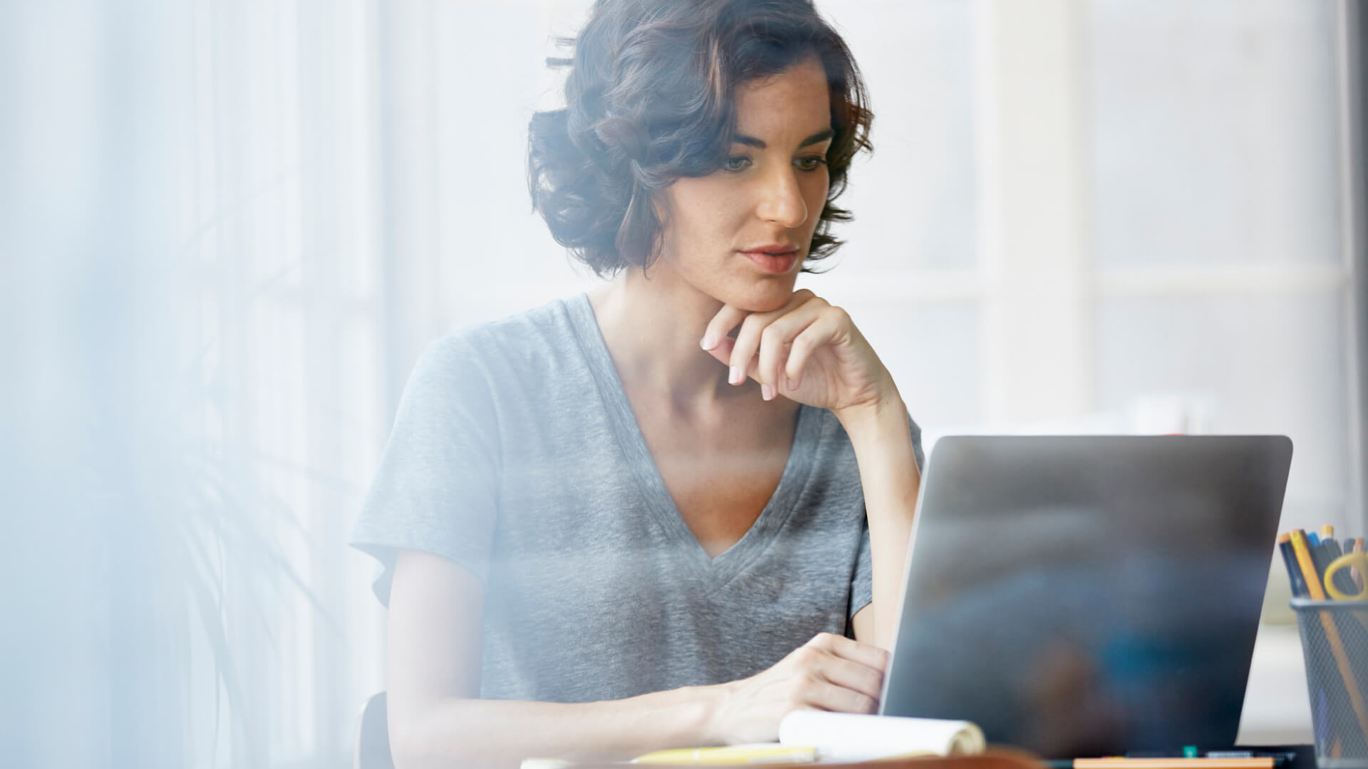 Woman looking thoughtfully at laptop.