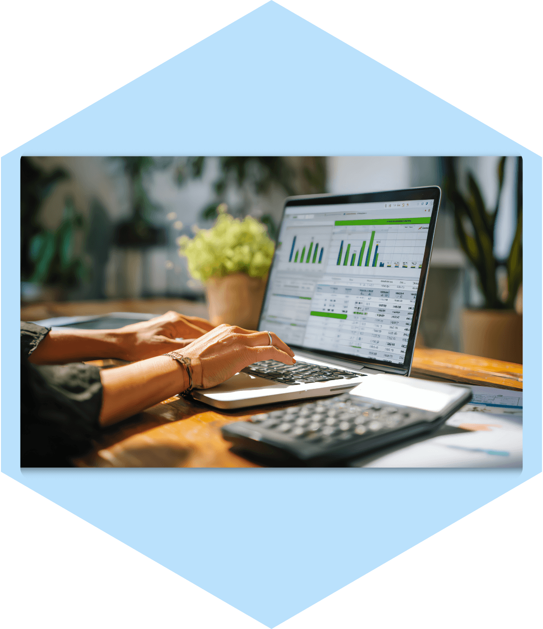 Hands typing on laptop with charts and data.