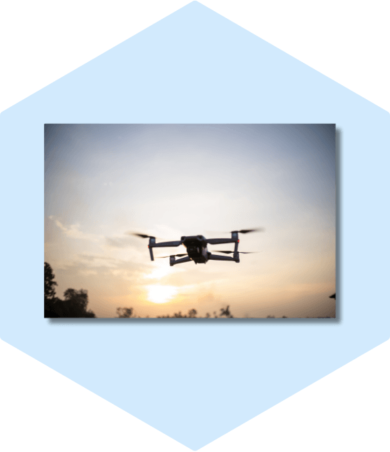 Silhouetted drone flying against sunset.