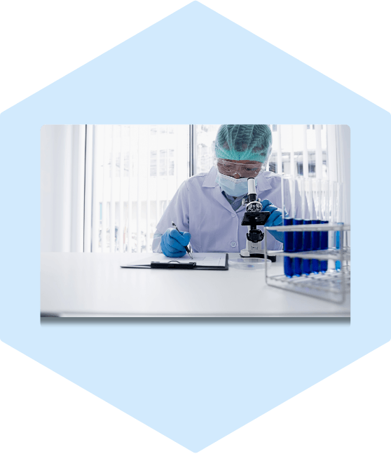 Researcher using microscope in lab, taking notes.