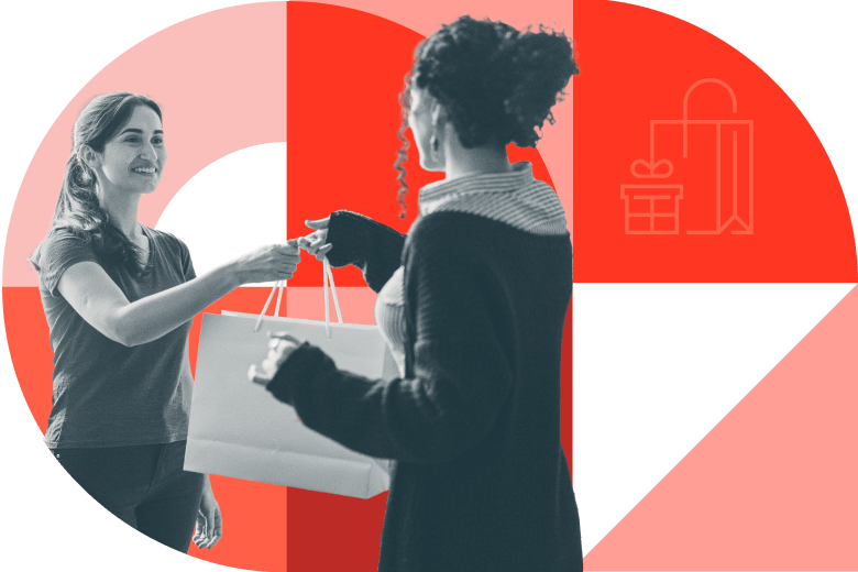 Two women exchanging a shopping bag.