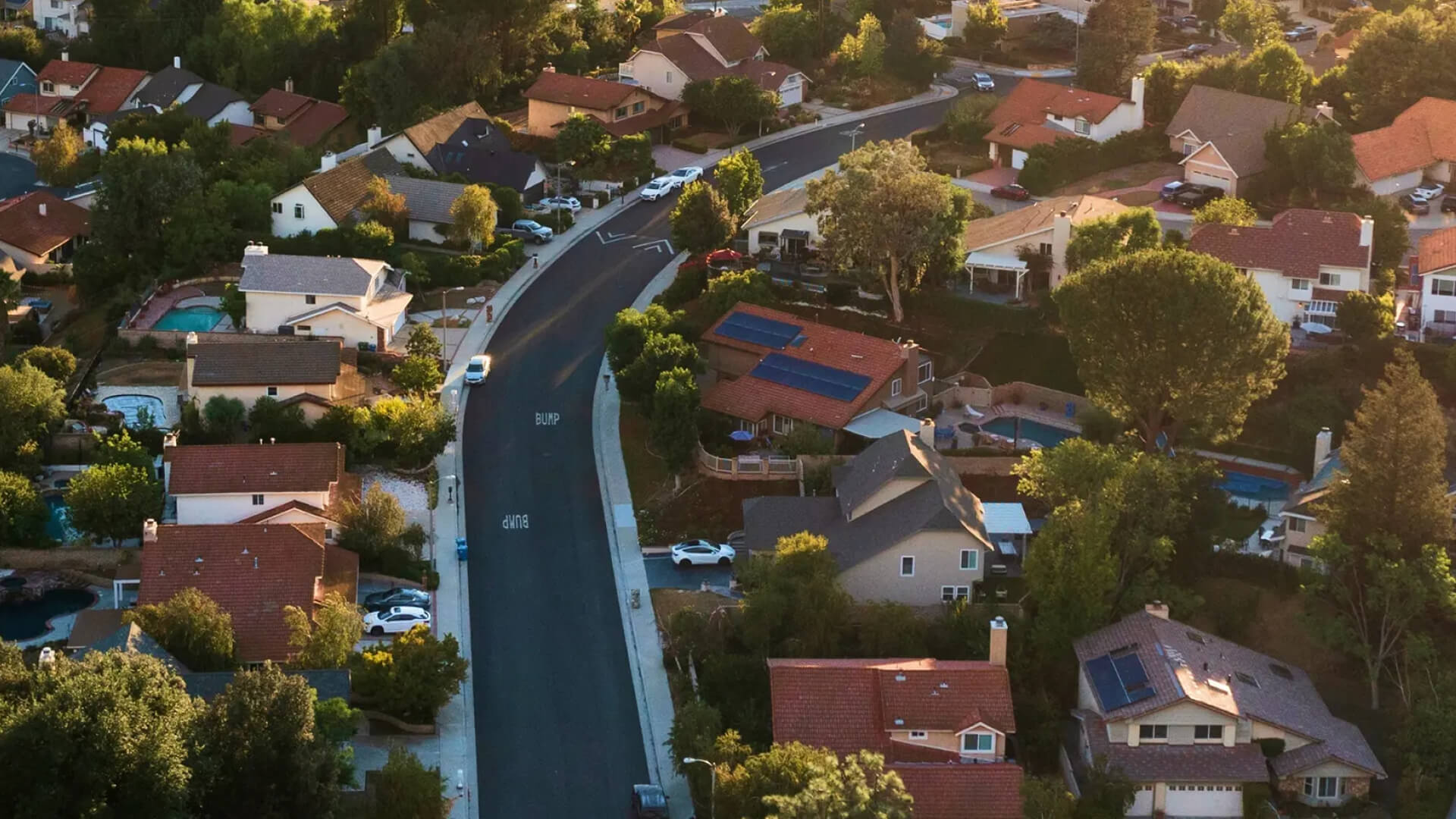 Winding road through a sunny suburban neighborhood.