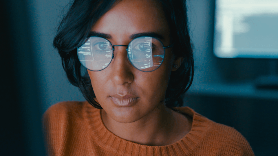 Woman with code reflected in glasses.