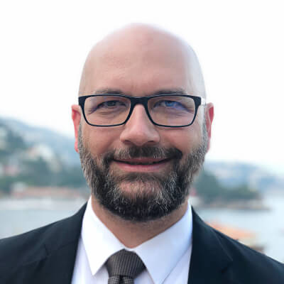 Smiling bald man with beard and glasses.