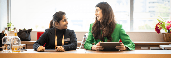 Two women smiling at each other at a table.