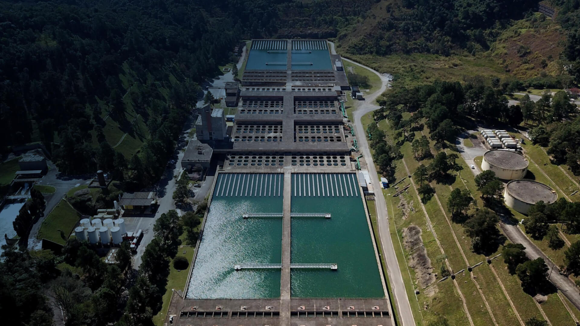 Large water treatment plant among green hills.