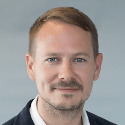 Headshot: Smiling man with mustache and blue eyes.