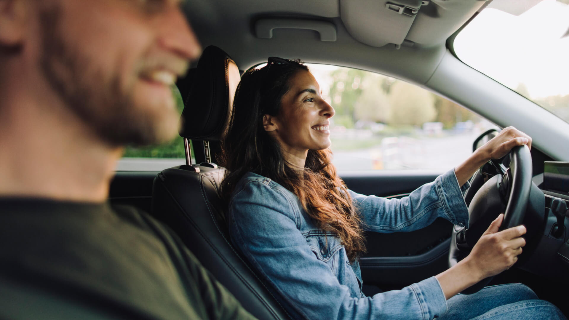 Smiling woman driving car with passenger.