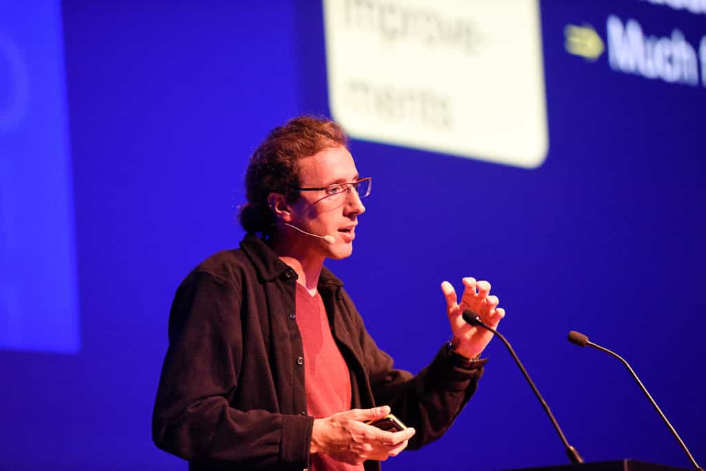 Gaël Varoquaux speaking onstage in front of microphones at the Amsterdam Spark Summit 2019.